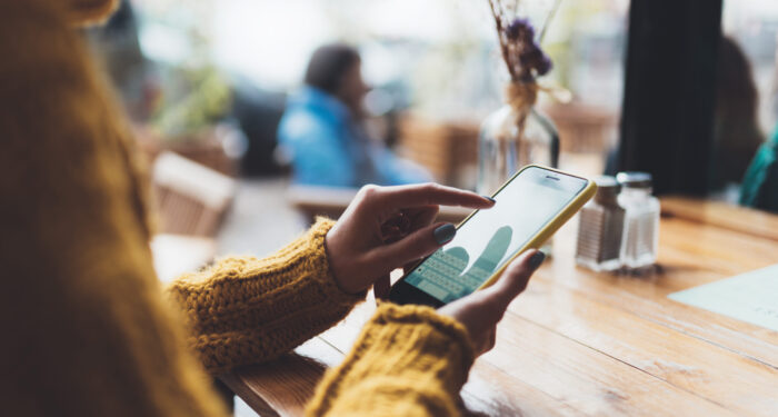 girl hold in hands yellow empty screen mobile phone close up, person type message on smartphone in sun cafe, relax tourist travels planning trip, hipster enjoy journey in cityscape, lifestyle holiday concept, internet online