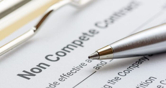 Blue pen, a gun or a pistol on a non compete contract. Noncompete contract is an agreement between employee and employer, not to enter into competition in subsequence business effort. Legal concept.