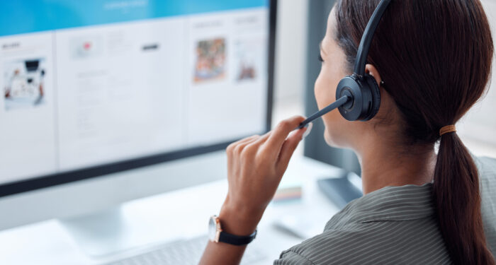 back of female consultant calling on headset in office