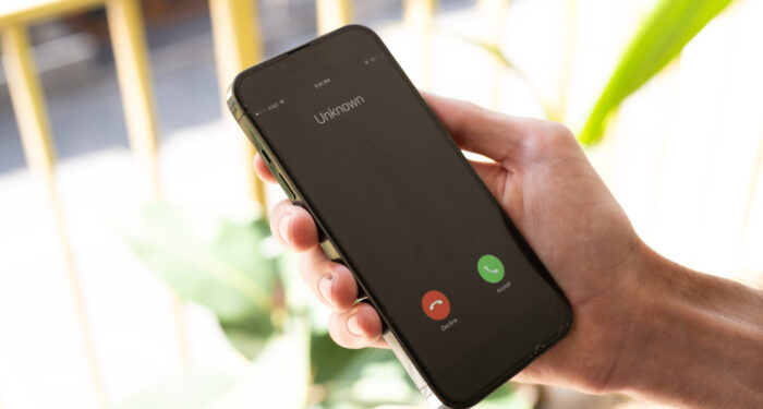 Fraud or fraudulent schemes. Close-up of a male hand holding a phone with an unexpected incoming call from an unknown