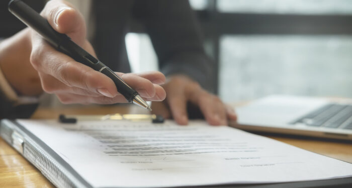 Close up business man reaching out sheet with contract agreement proposing to sign.Full and accurate details, individual who owns the business sign personally,director of the company, solicitor.