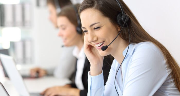 Telemarketing operator talking working at office with other workers in the background